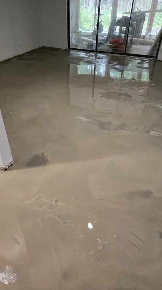 Flooded interior room; brown water covers the floor, with a glass door in the background.