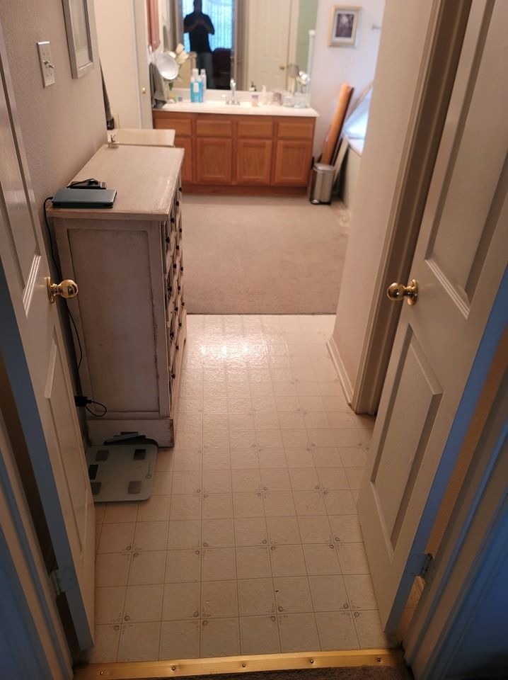 Entryway leading to bathroom with dresser and scale. Wooden cabinetry and carpet.