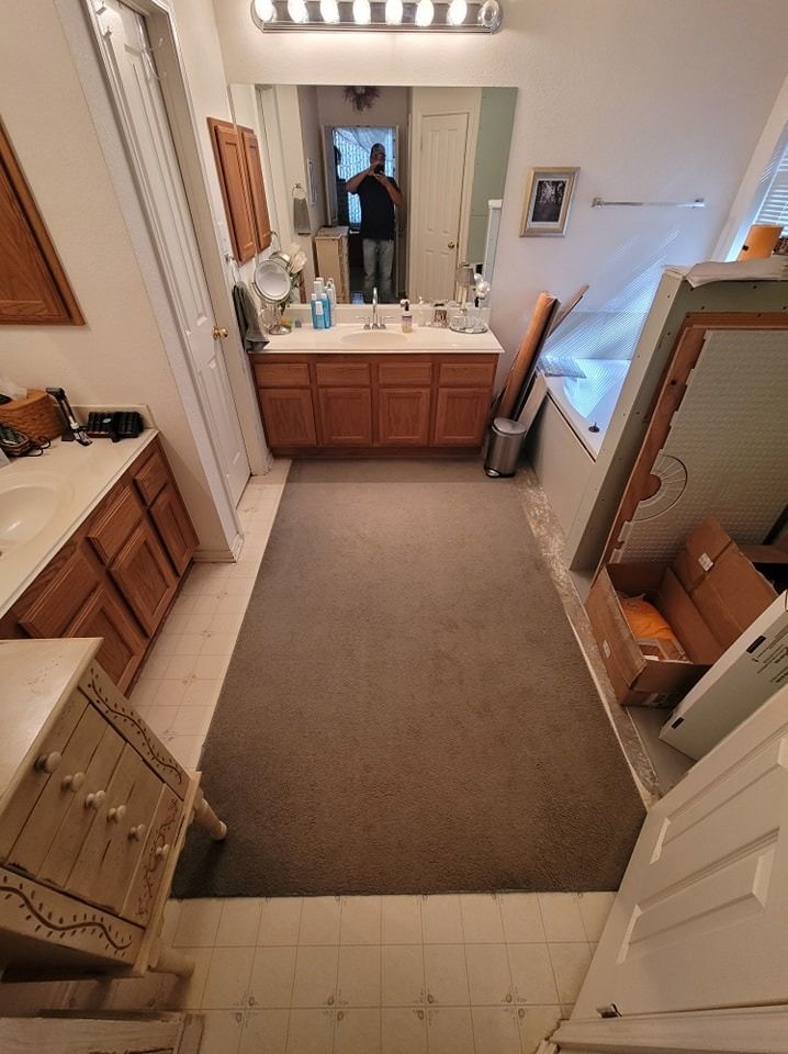 Bathroom with brown cabinets, long rug, and partially visible person in mirror.