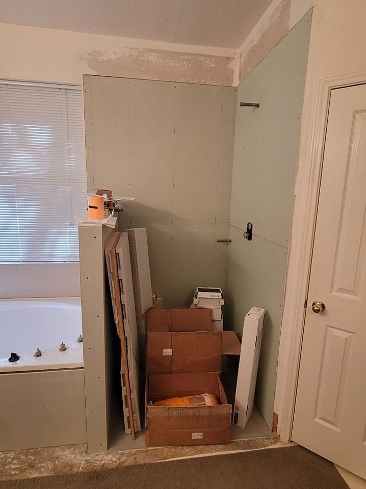 Bathroom renovation in progress. Green drywall installed, boxes and materials stacked.