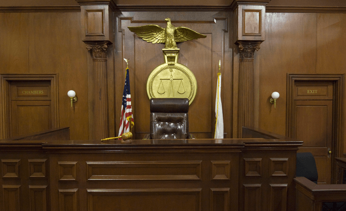 Empty courtroom with chair of judge and flags