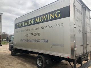 A statewide moving truck is parked in a dirt lot