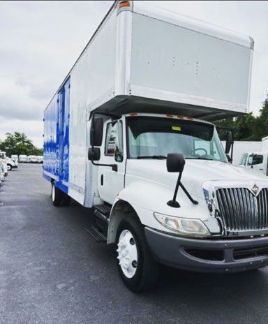 A white and blue moving truck is parked in a parking lot