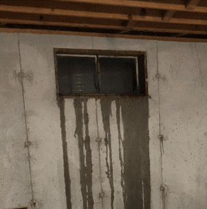 Water stains and possible dampness from a window on a concrete basement wall.