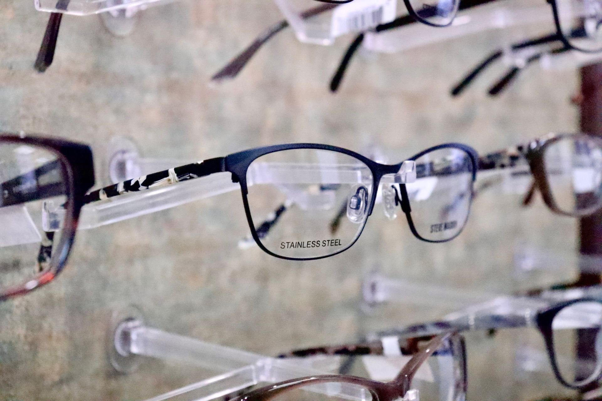 A row of glasses hanging on a rack in an optical store.