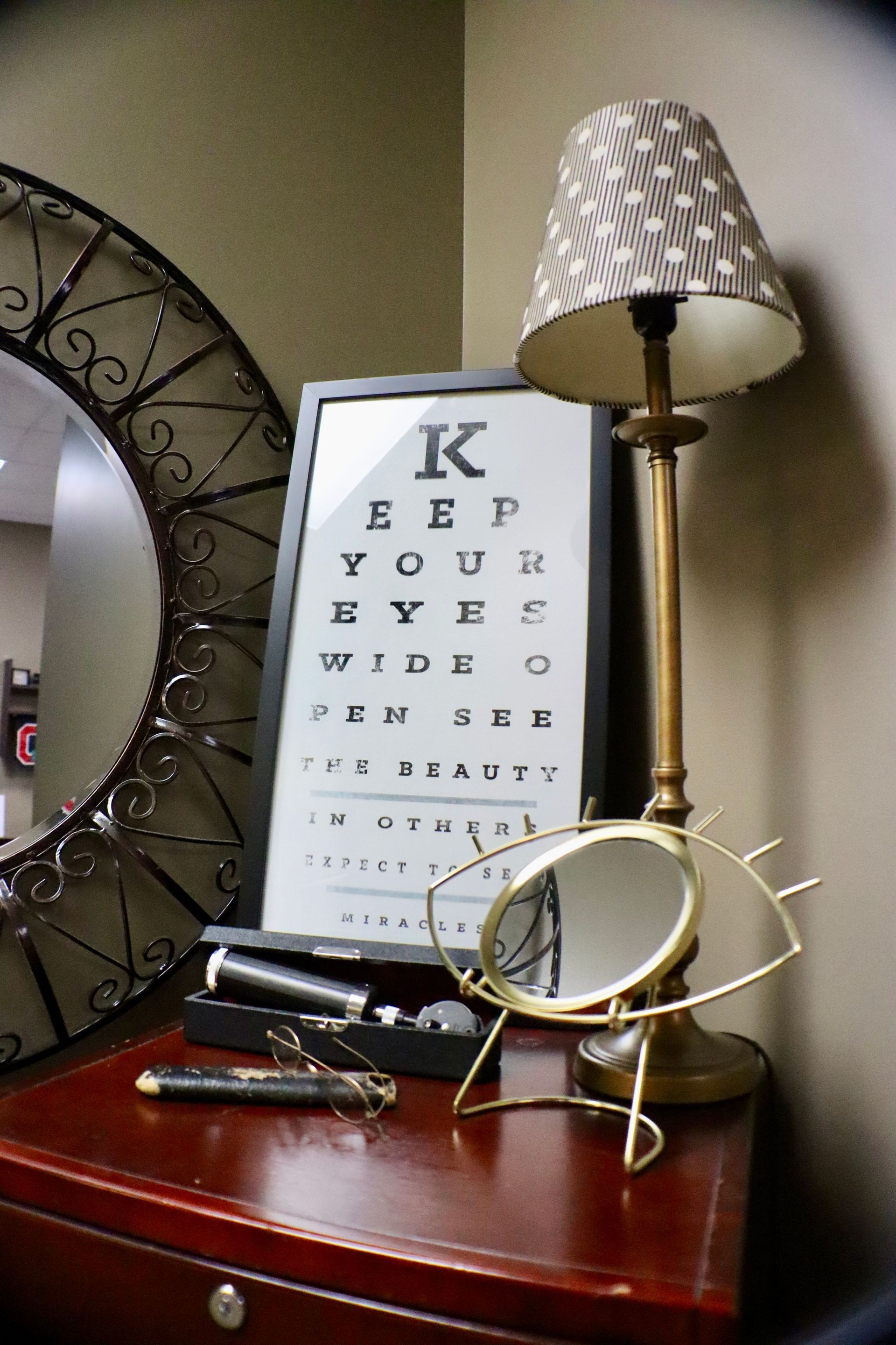 A table with a lamp and a sign that says keep your eyes wide