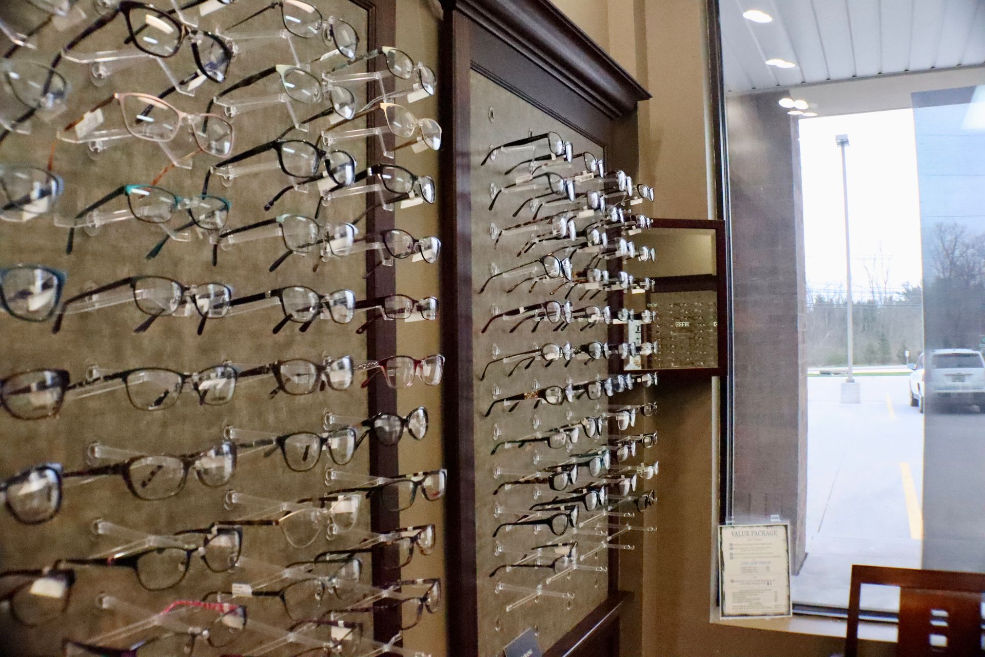 A row of glasses hanging on a wall in an optical shop.