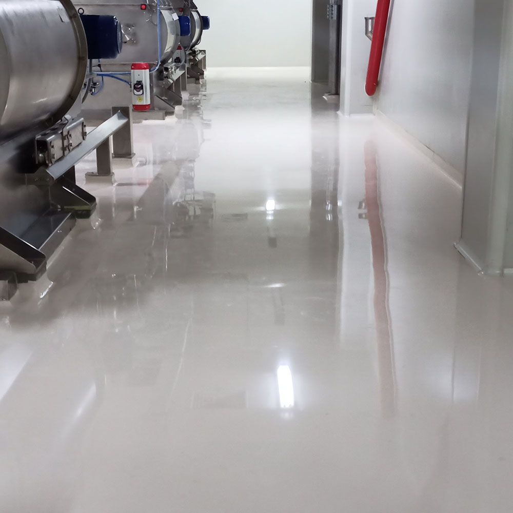 Shiny white industrial floor reflecting equipment and hallway.