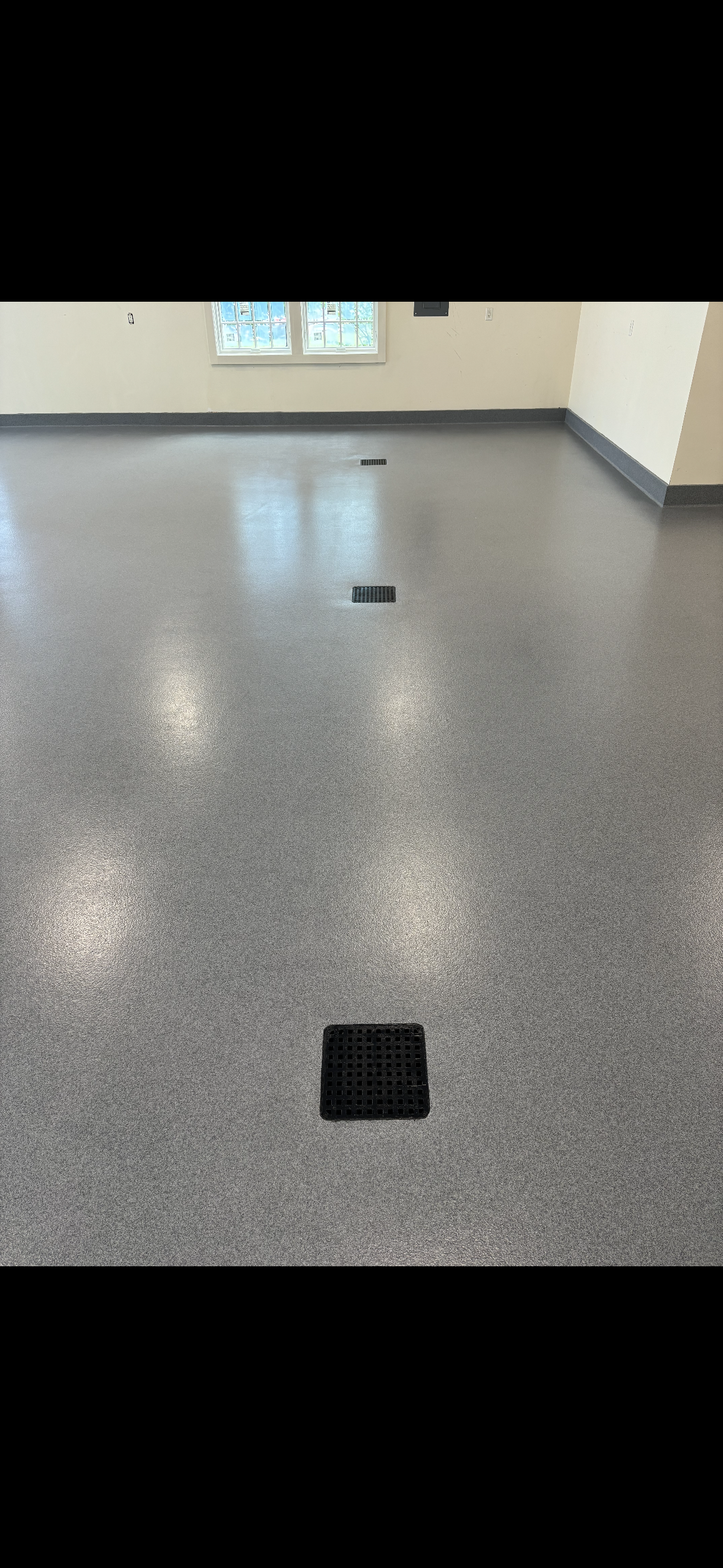 Grey flecked floor with several dark square floor vents.