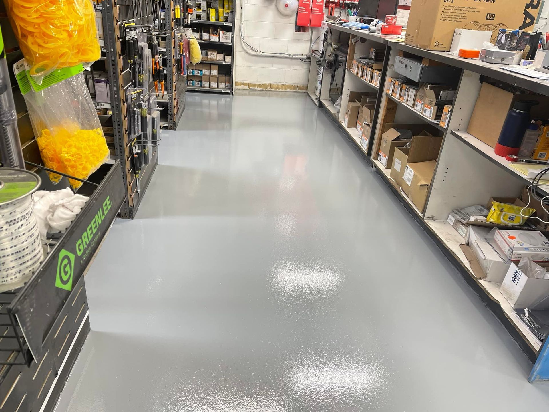 Gray floor in a store aisle with shelving on both sides. White debris is scattered across the floor.