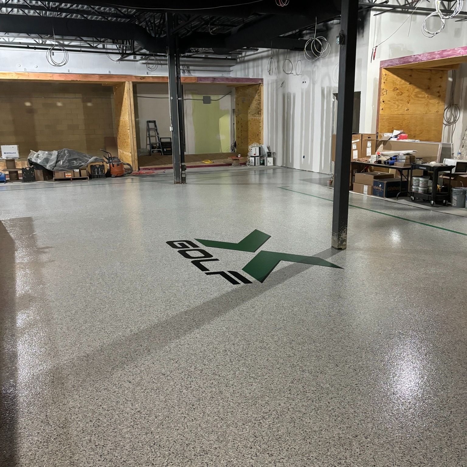 Spacious room with polished concrete floor, a logo, and areas under construction.