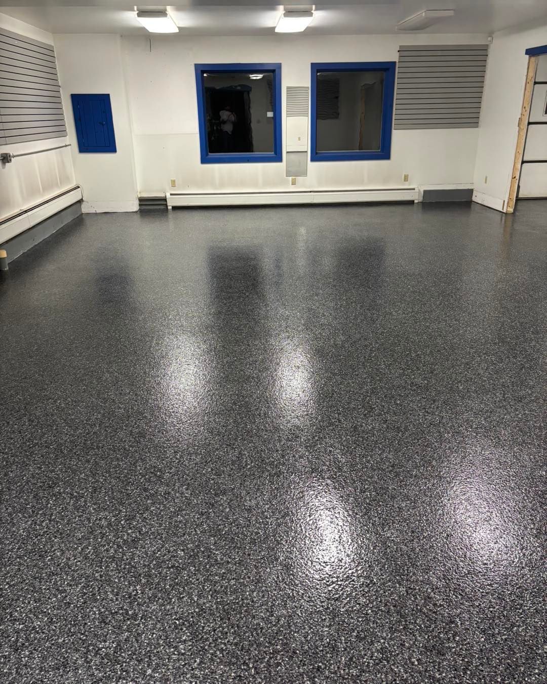 Gray speckled epoxy floor in a room with blue-framed windows and white walls.