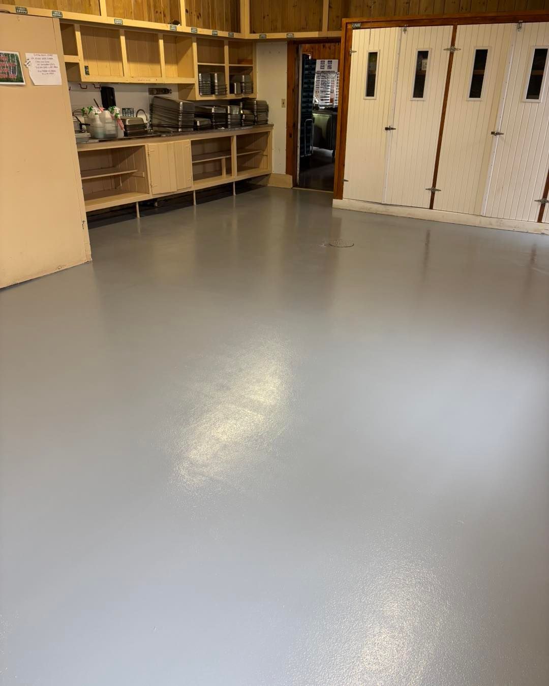 Empty room with light gray floor, built-in wooden shelves, and white cabinets.