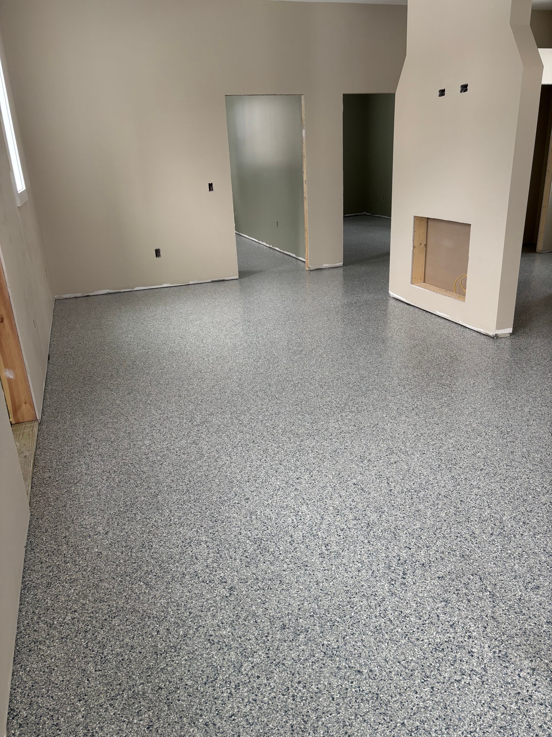 Room with speckled gray epoxy flooring, off-white walls, and doorways.