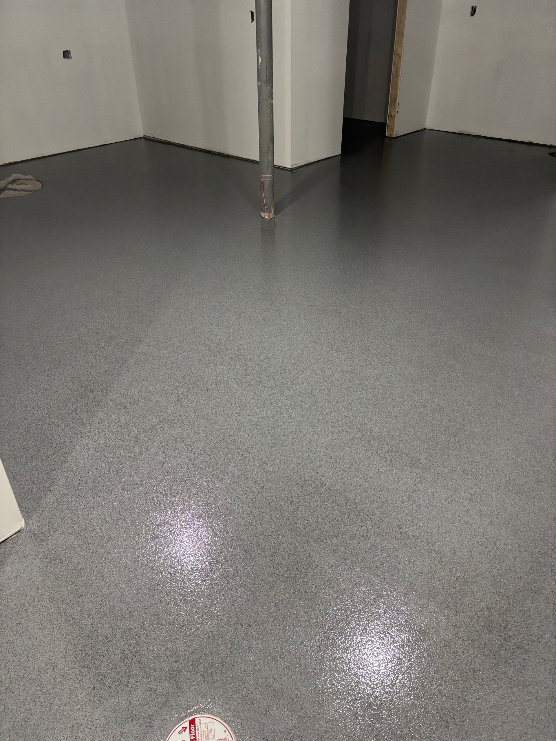 Gray speckled epoxy floor in a room with white walls, reflective sheen.
