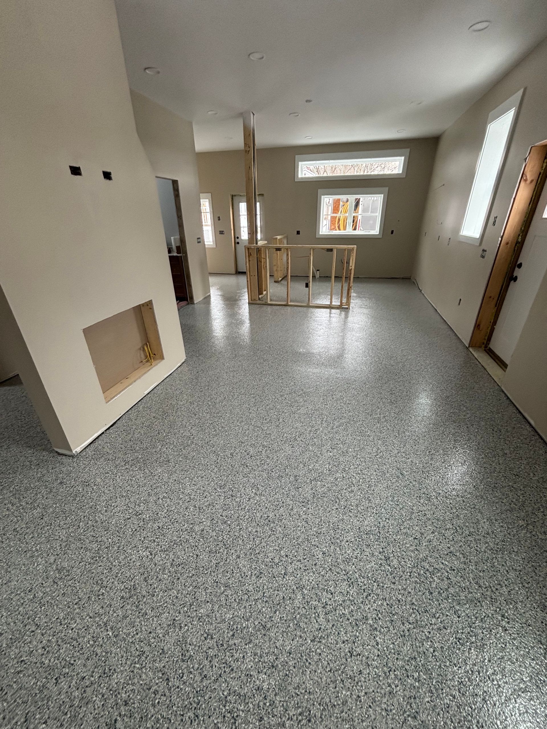 Empty room with speckled grey flooring, light-colored walls, and a fireplace.