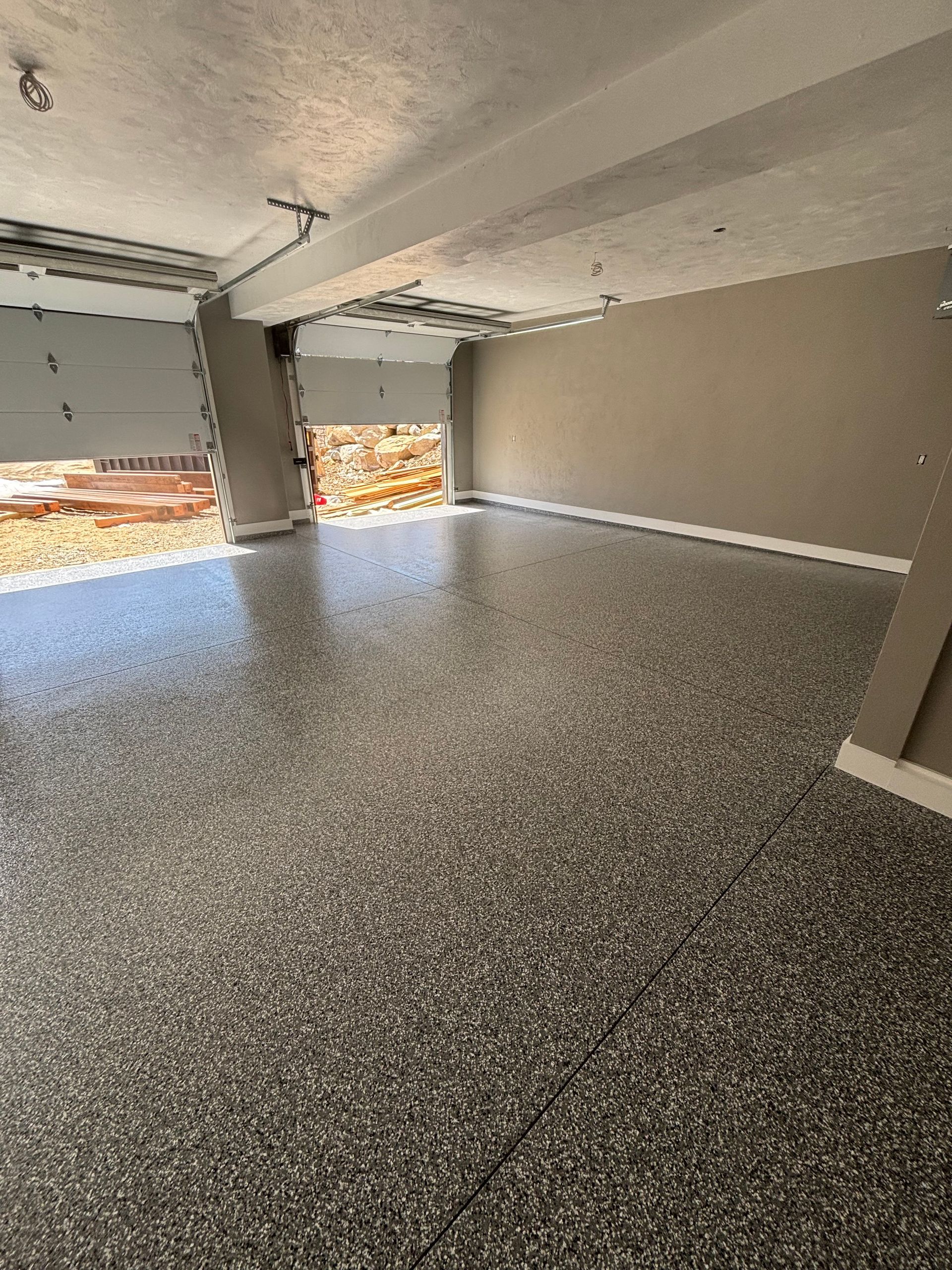 Garage interior with speckled epoxy floor, open door, and tan walls.