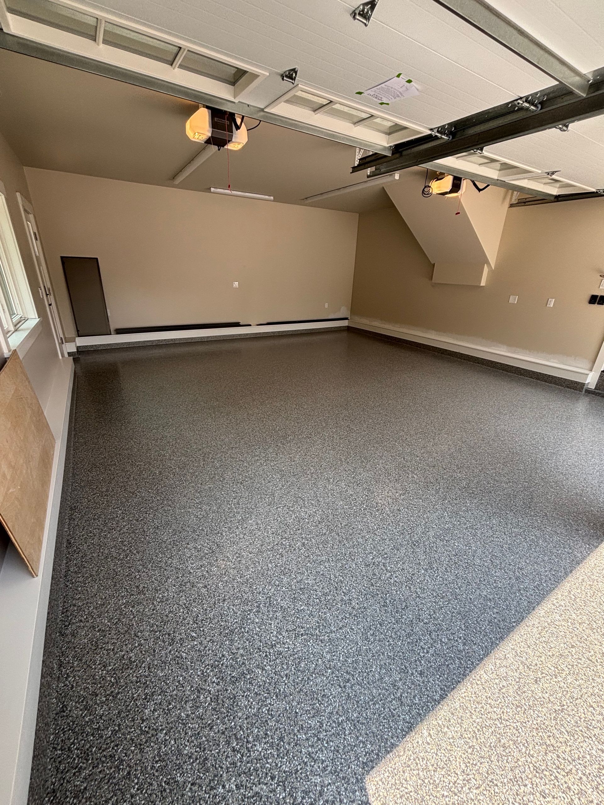 Empty garage with speckled gray floor and tan walls.
