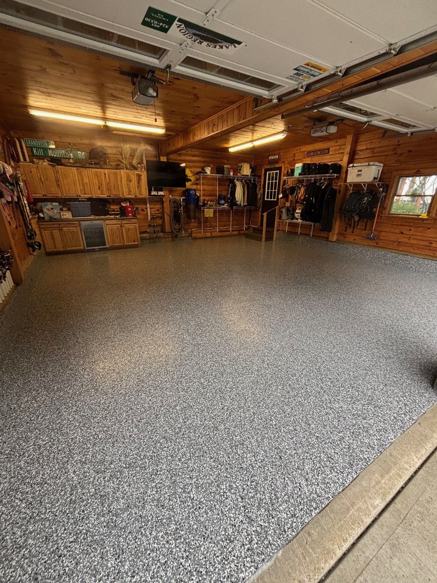 Garage interior with speckled gray floor and wooden cabinetry and ceiling.