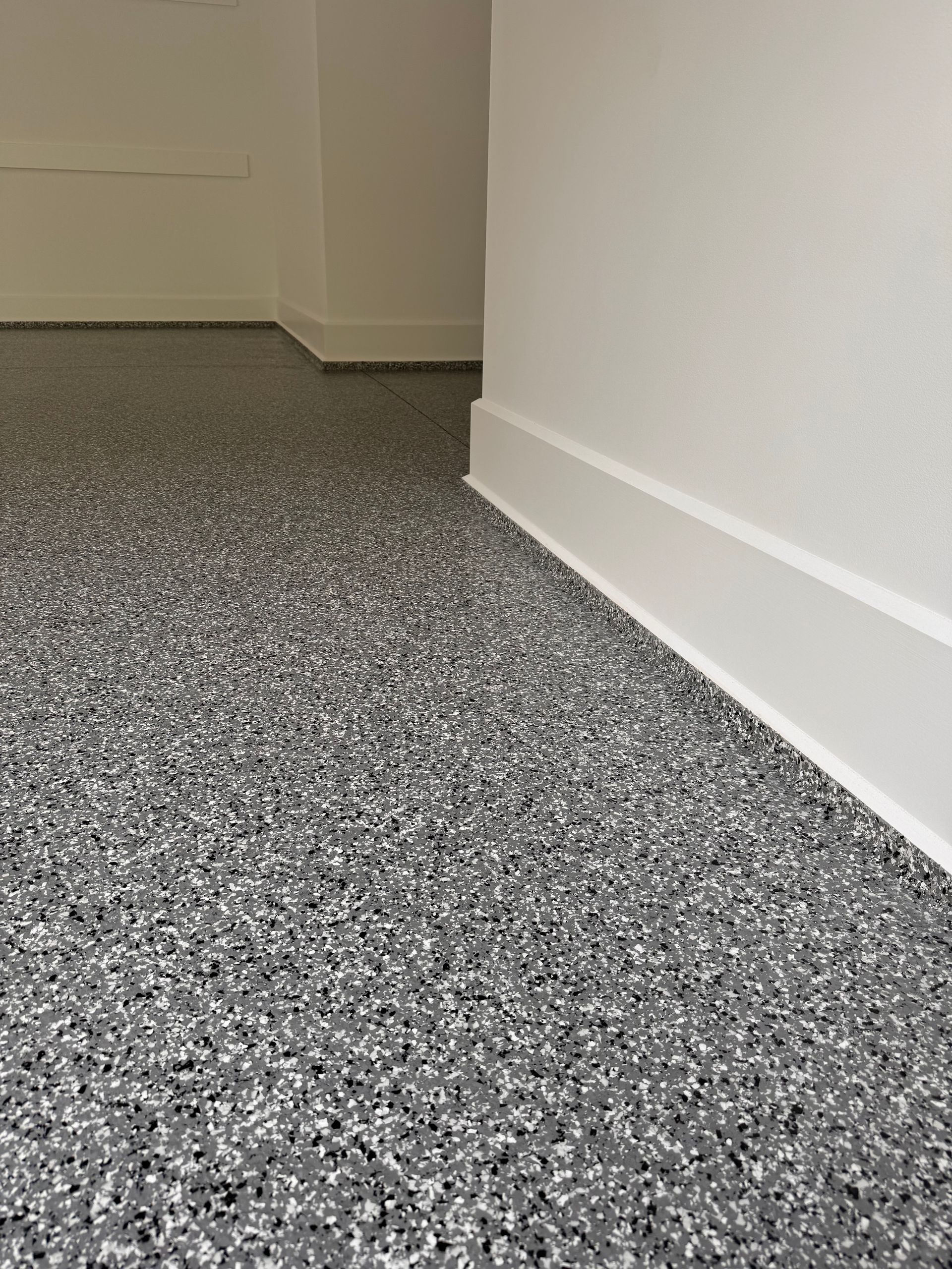 Gray and white speckled epoxy floor with white baseboards and walls.