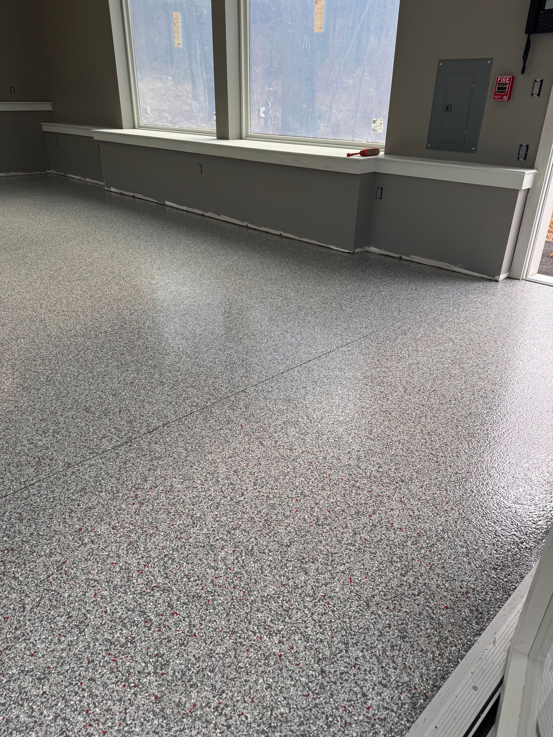 Gray speckled epoxy floor in a room with a window and electrical box.