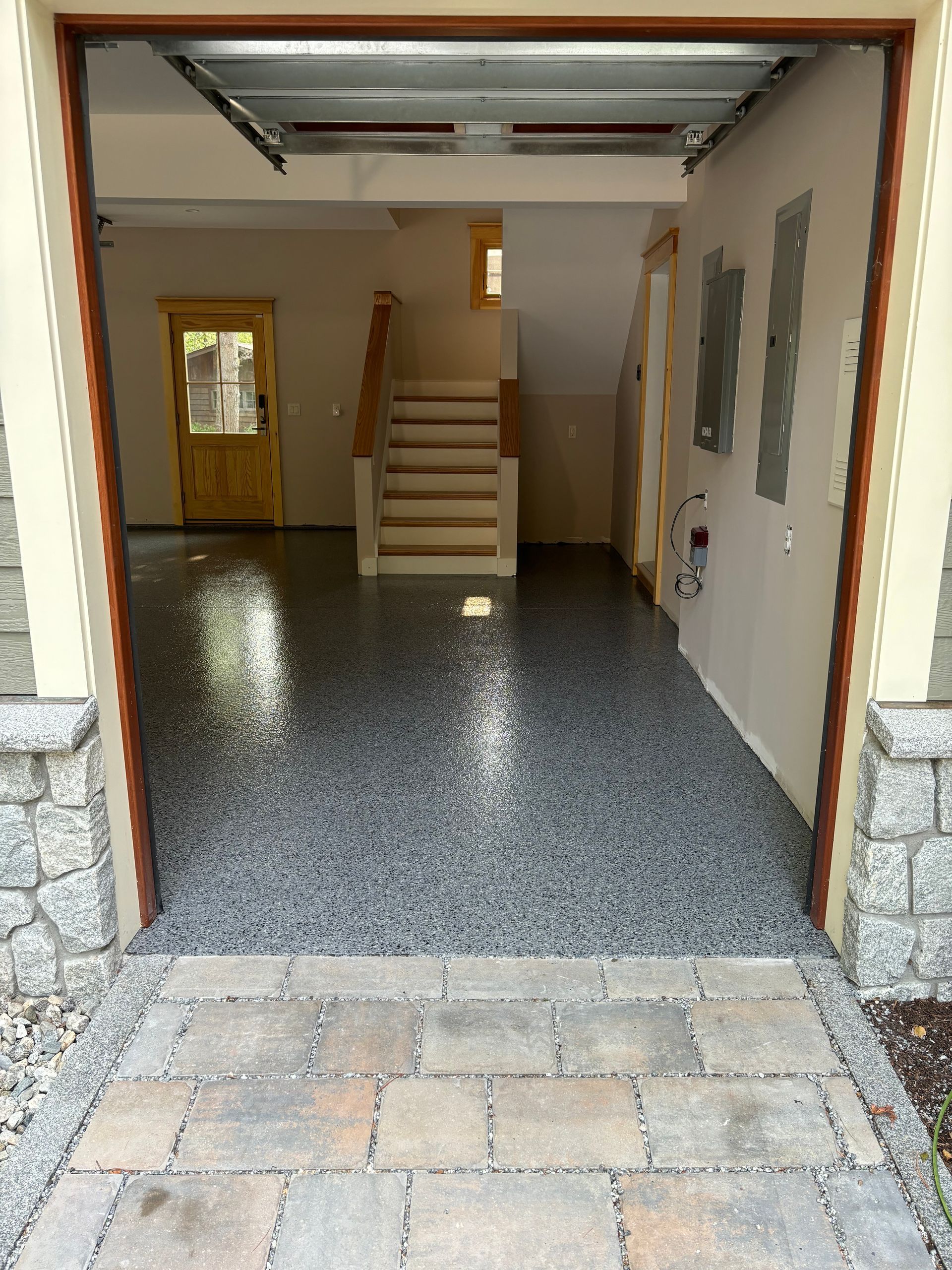 Garage interior with epoxy floor, stairs, wooden door, and stone facade.