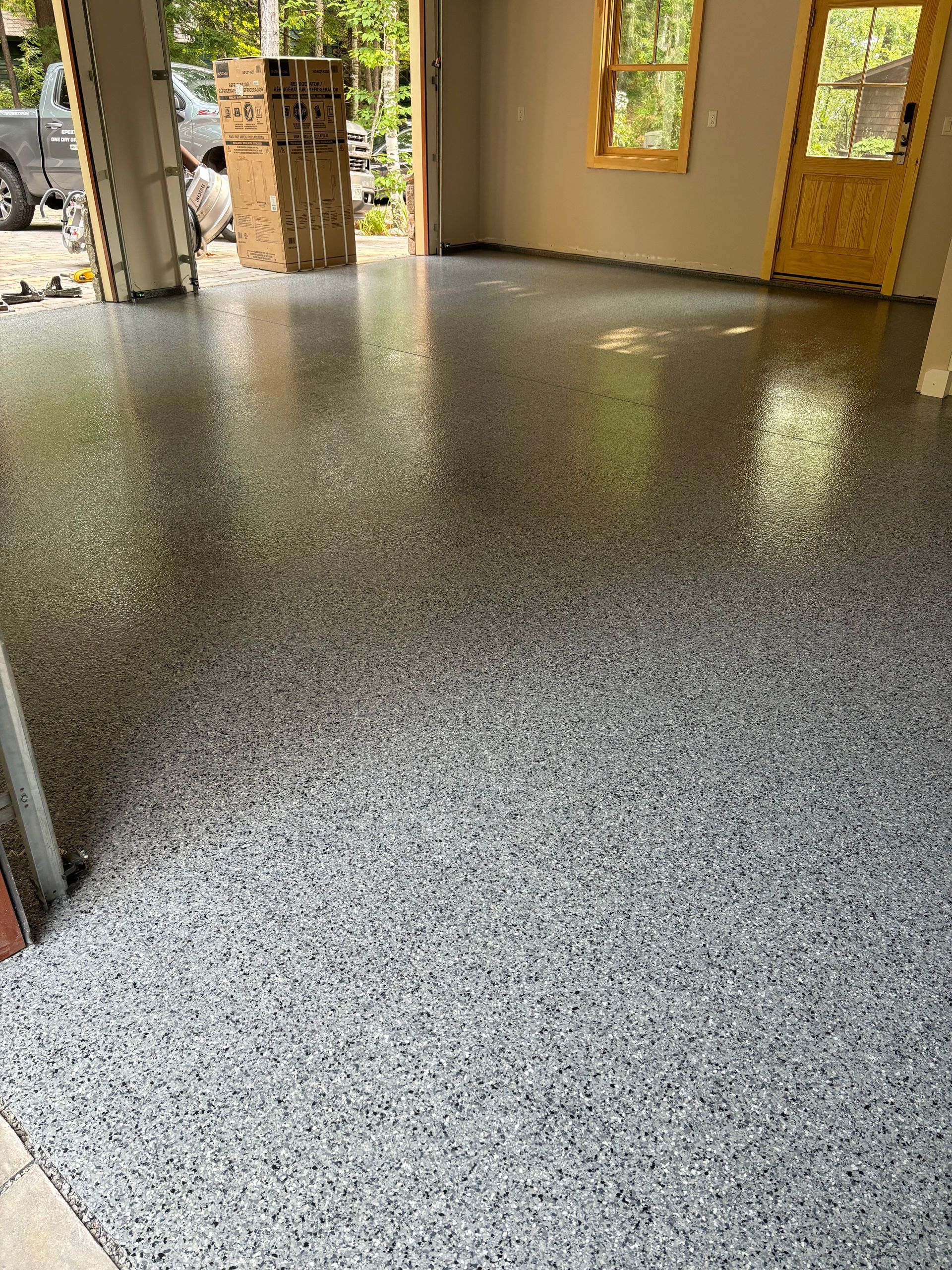 Garage with speckled gray epoxy flooring, sunny windows, and a yellow door.