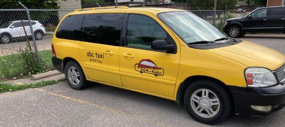 A yellow taxi cab is parked in a parking lot