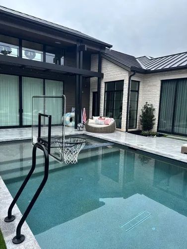 A modern home with a pool and basketball hoop on a gray, overcast day.