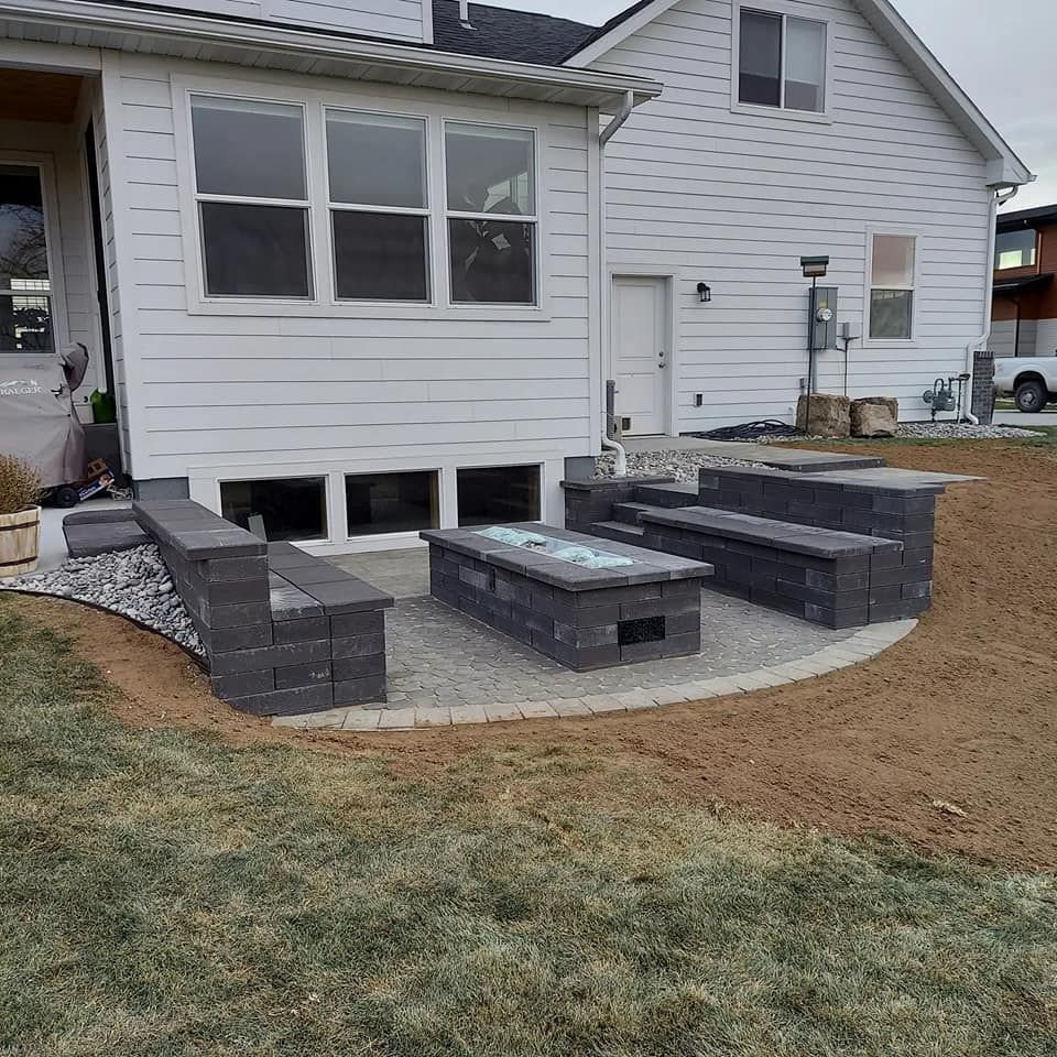 Backyard patio with fire pit, built-in seating, and a white house.