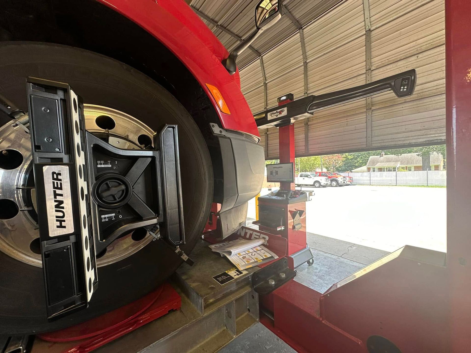 Red truck tire in a Hunter wheel alignment machine at a repair shop.