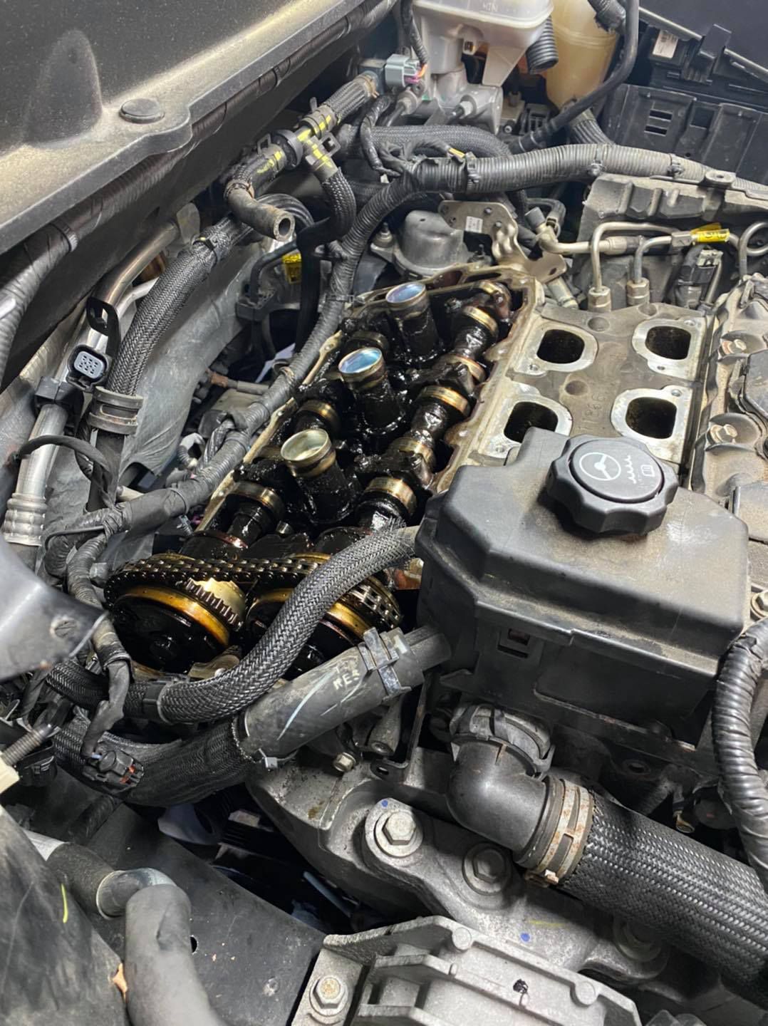 Open car engine with exposed components, covered in oil.