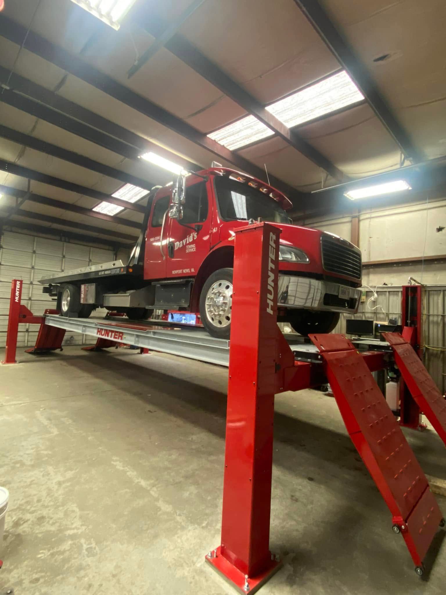 Red tow truck on a red car lift in a garage.