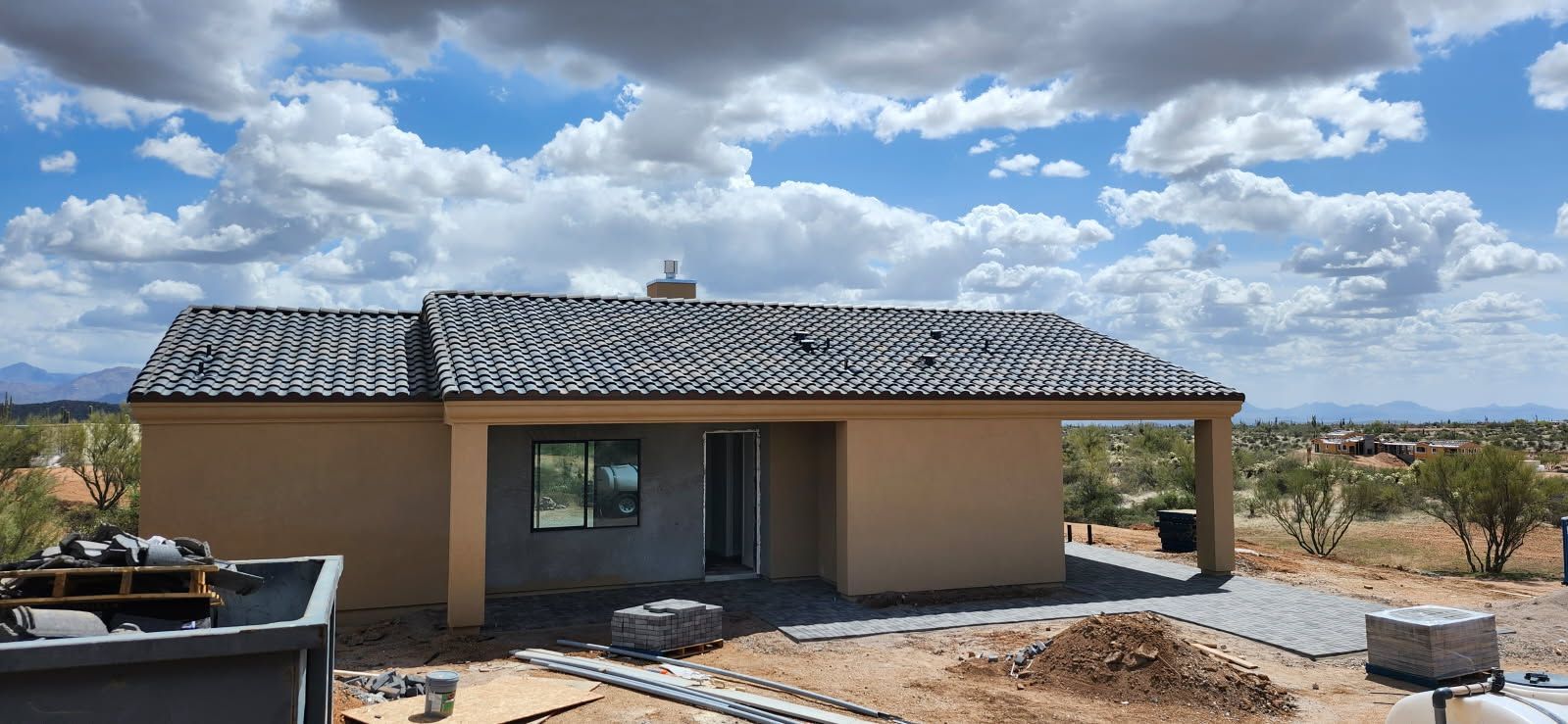 A small house with a tiled roof is being built in the desert.