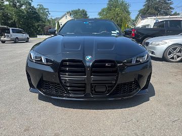 A black BMW M3 parked in an outdoor lot on a sunny day, showcasing its prominent vertical front grille.