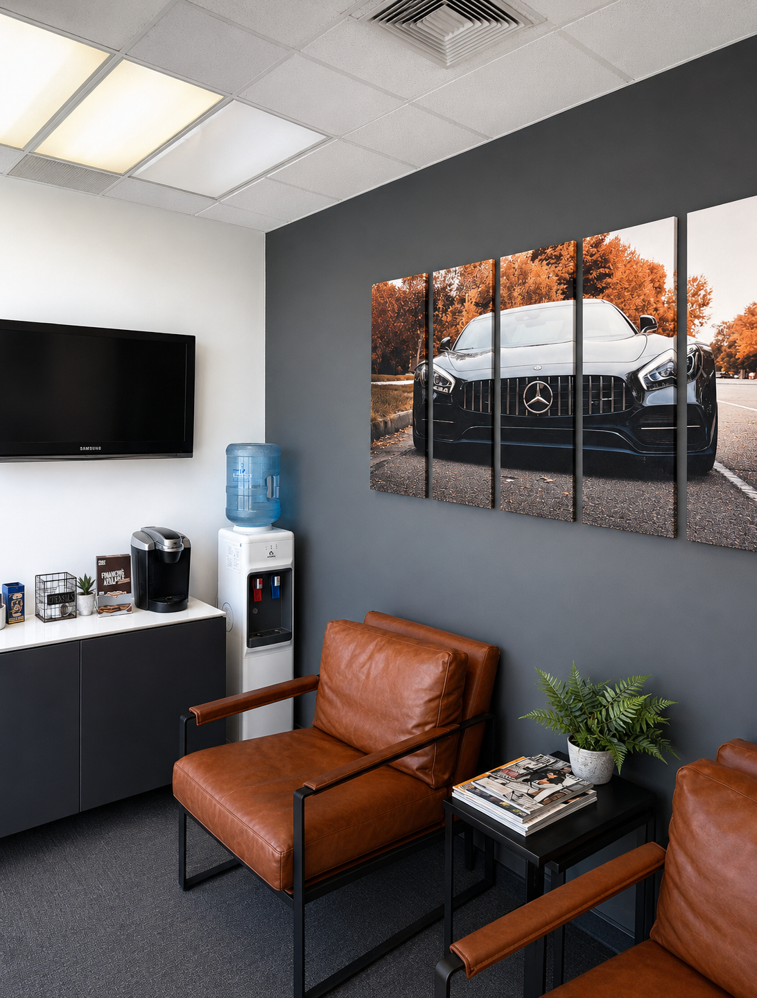 Modern office waiting area with brown leather chairs, coffee station, water cooler, and framed wall art.