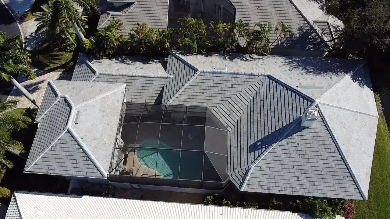 Aerial view of a house with a gray metal roof surrounding a central courtyard or pool area.