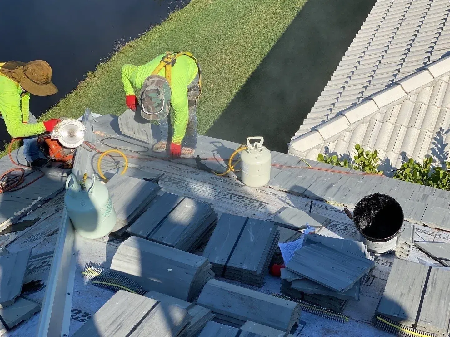 Workers installing materials on a rooftop beside safety gear and buckets