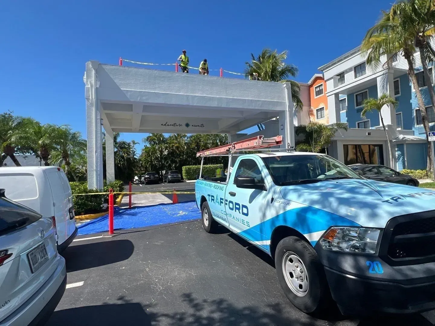Rally stage with police truck in front, workers on a white canopy, and blue carpet under a bright sky