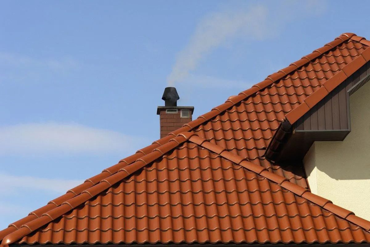 Red tiled roof and chimney against a blue sky