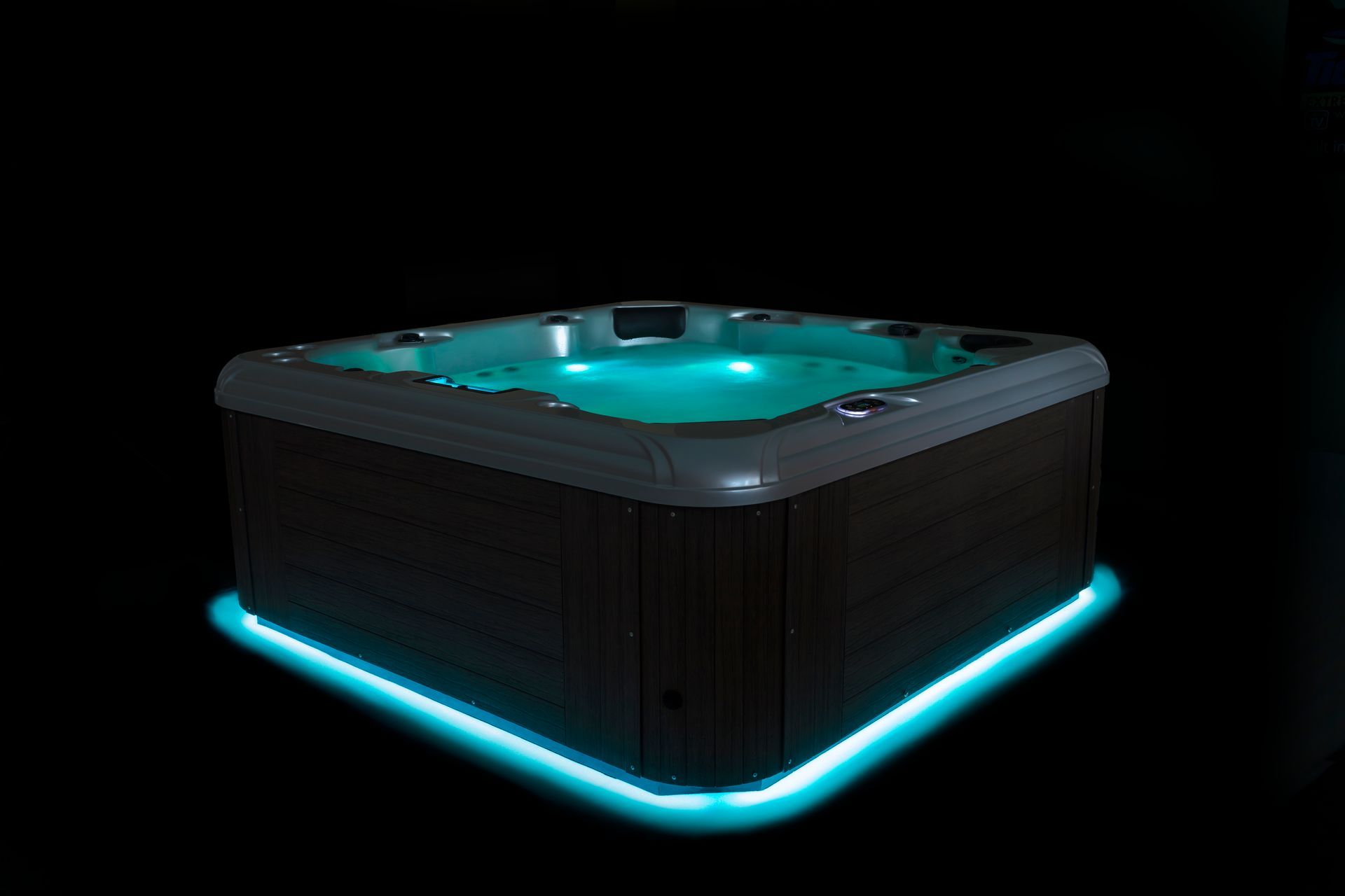 A lit-up square hot tub with blue lighting, set against a black background.
