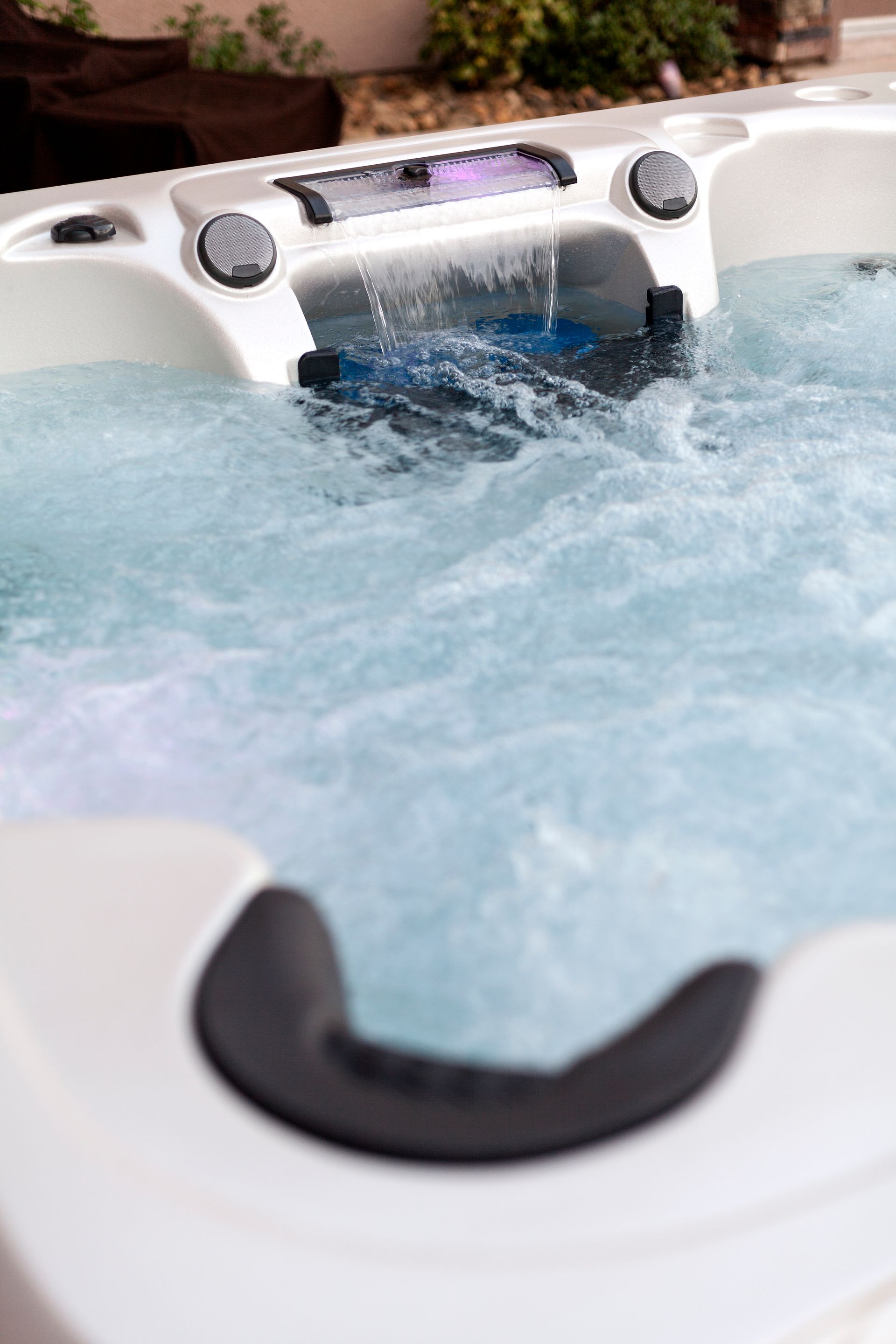 A white hot tub with bubbling water and a water feature, seen up close.