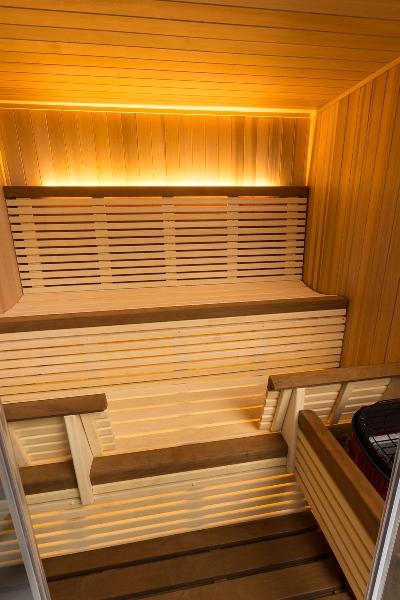 Wooden sauna interior with benches and warm lighting.