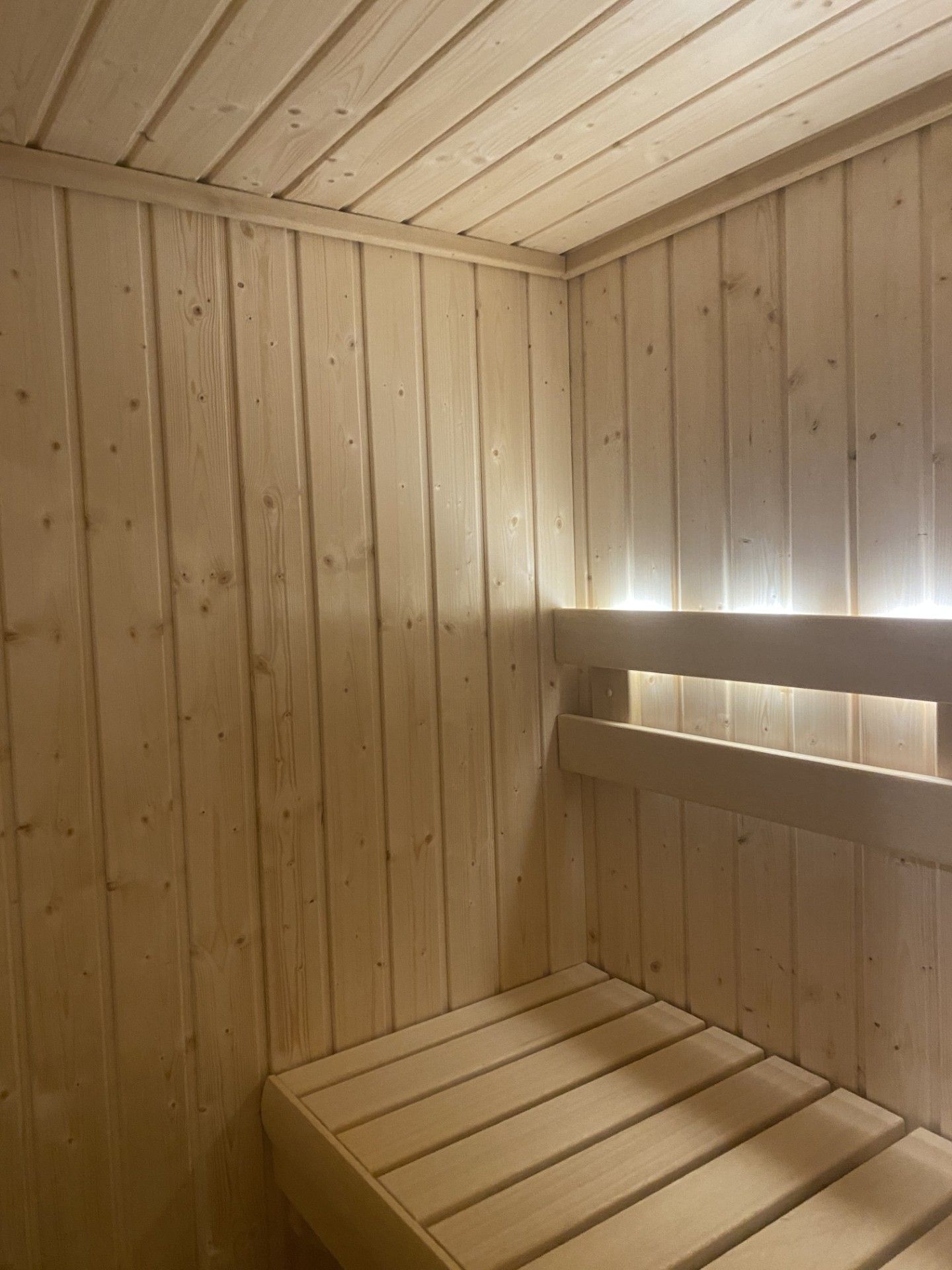 Wooden sauna interior with benches and ceiling.