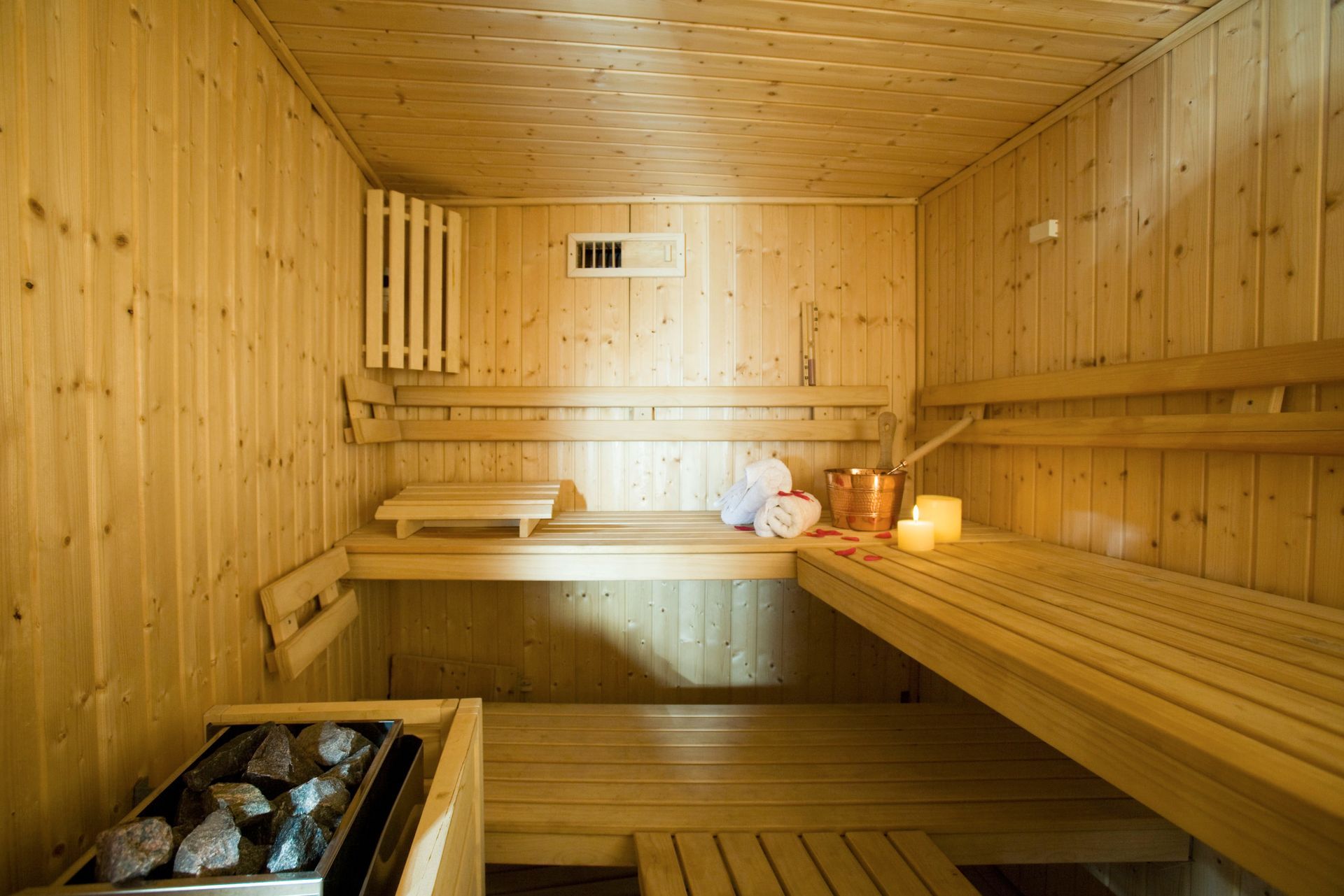Wooden sauna with benches, rocks, and towels.