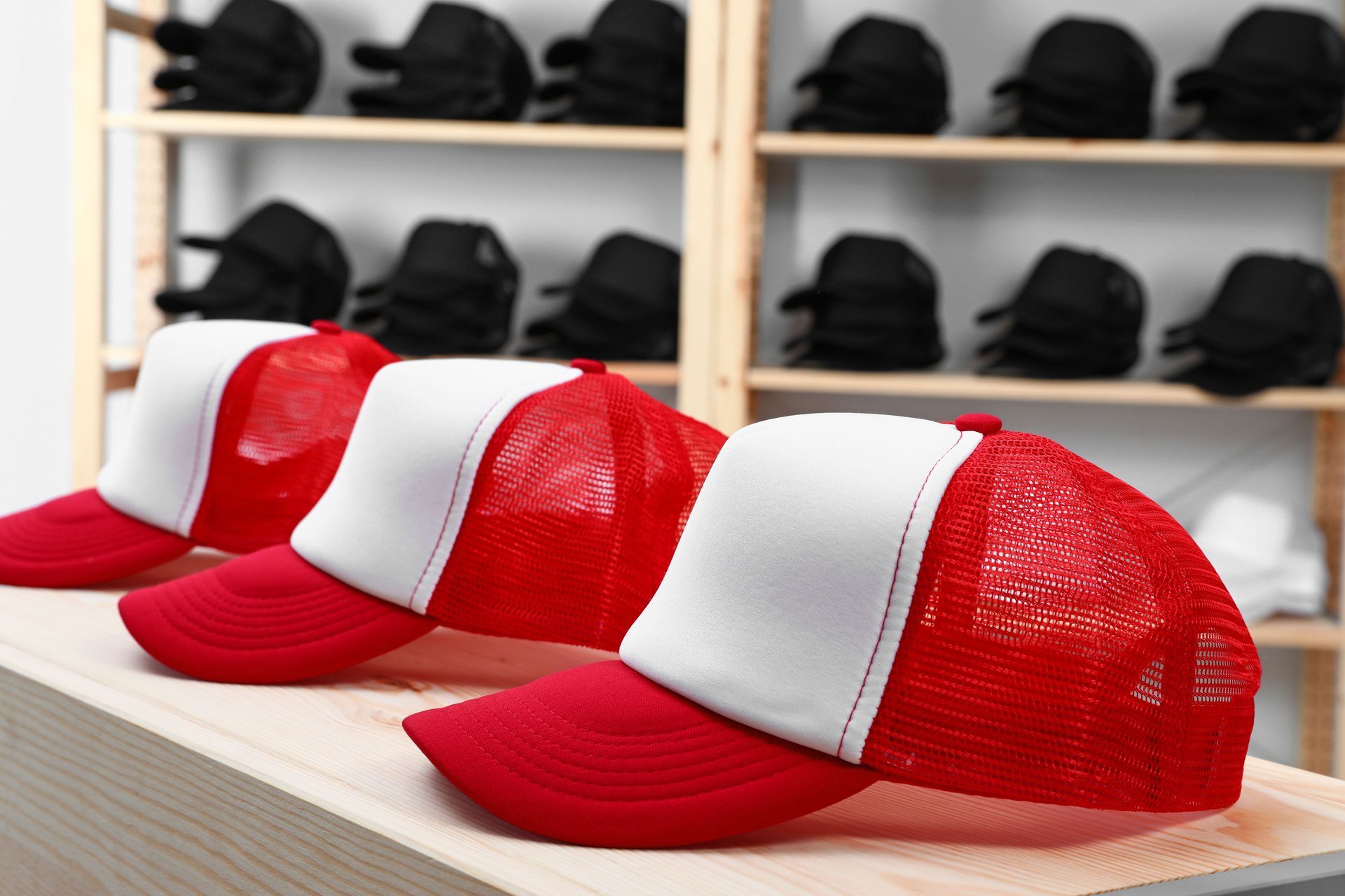 Three red-and-white trucker hats on a shelf in a store display