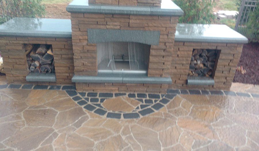Outdoor stone fireplace with wood storage and flagstone patio.