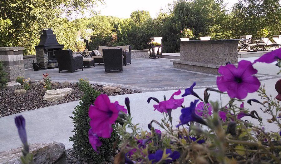 Outdoor patio with flowers, seating area, fireplace, and bar.