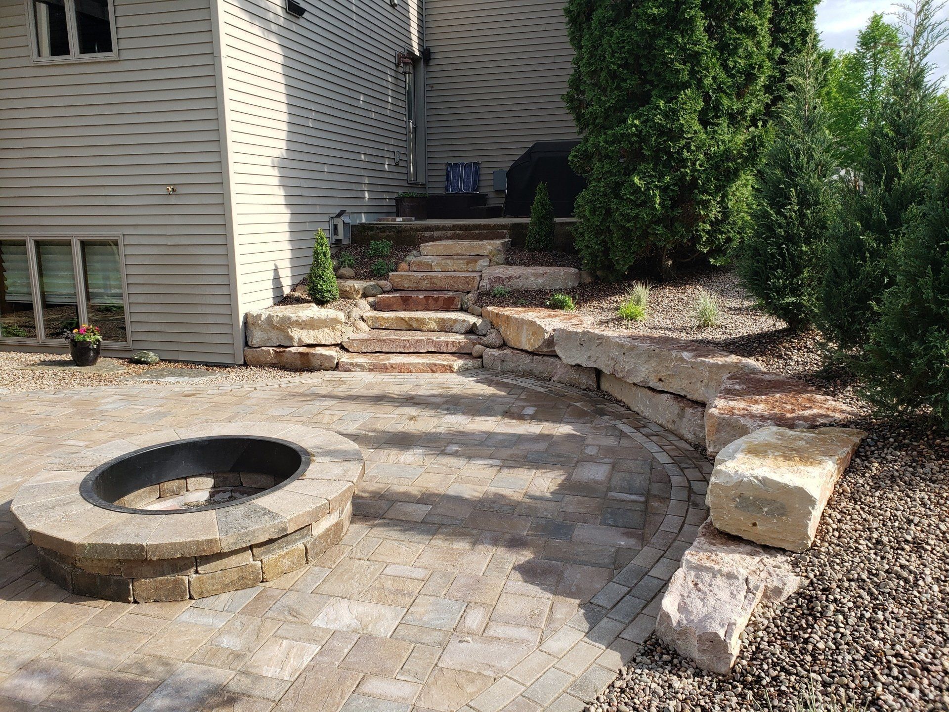 Backyard patio with fire pit, stone steps, and retaining wall.