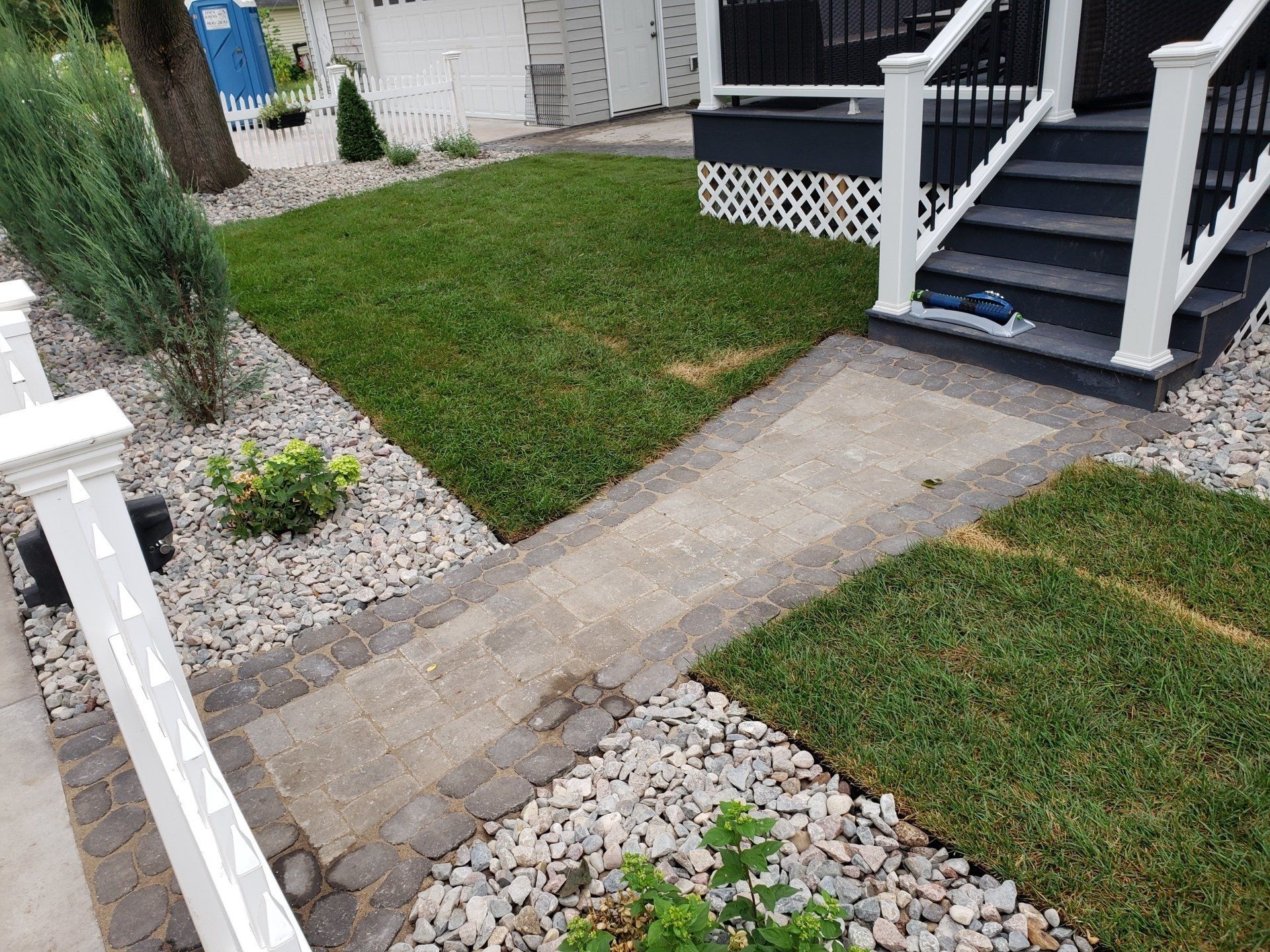 Stone pathway and steps leading to a house entrance. Lawn and rock landscaping surround the pathway.
